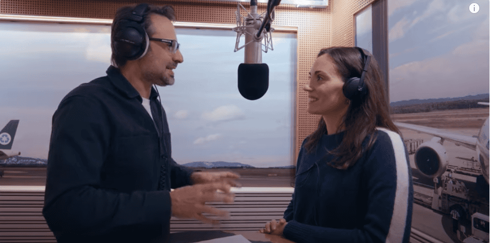 Due persone che parlano in studio di registrazione con cuffie e microfono.